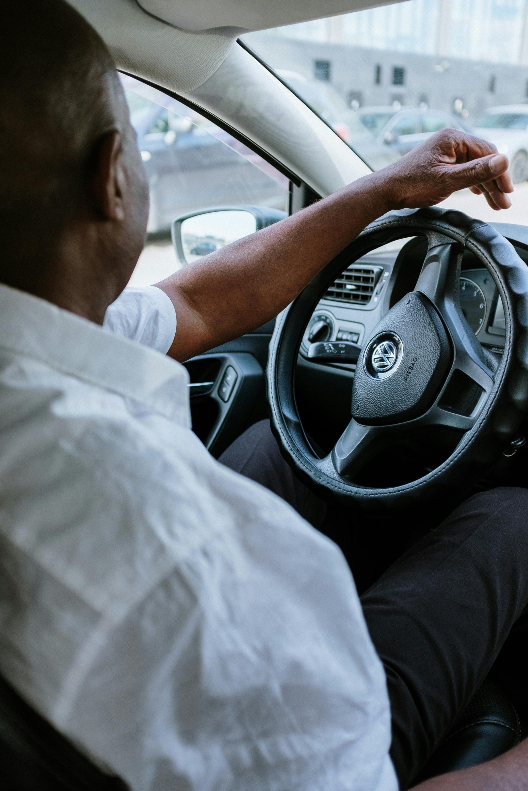 A man driving a vehicle, highlighting the steering wheel and car interior.